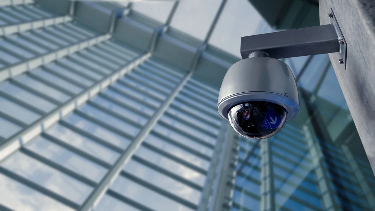 Dome surveillance camera mounted beside a glass facade